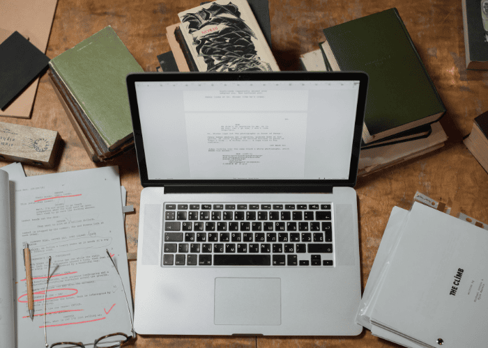 How to edit a book with a marked-up manuscript, revision notes, and digital editing on a laptop